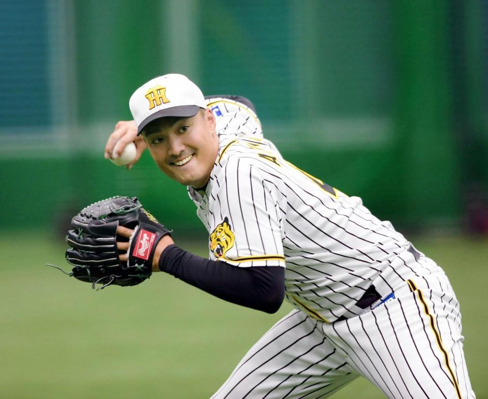　ノックを受け、送球する阪神・秋山拓巳＝甲子園