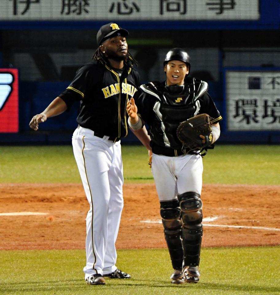 　勝利を決めてタッチを交わす阪神・ドリス（左）と梅野