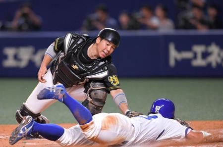 ７回、阪神・二塁手の糸原から送球を受け、本塁を狙う中日・三走の亀澤（下）にタッチする阪神・捕手の梅野。リクエストの結果、セーフの判定に変わる＝ナゴヤドーム