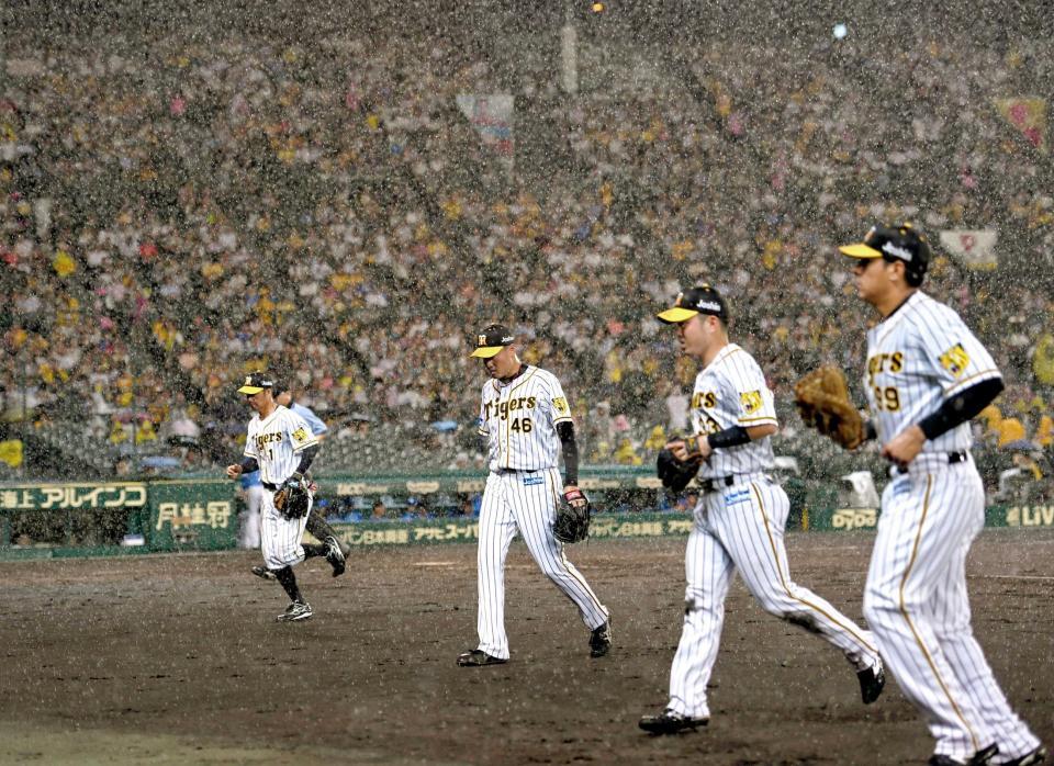 　３回、激しい雨で試合が中断し、ベンチへ戻る秋山（中央）ら阪神ナイン。この後、ノーゲームとなる