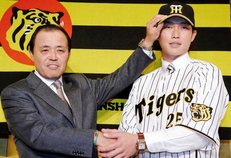 　阪神への入団会見でユニホームに袖を通し、岡田監督（左）と握手を交わす新井＝２００７年