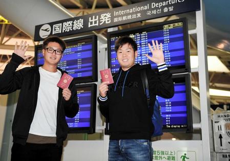 　出国を前に、パスポートを持って手を振る西（右）と山田（撮影・田中太一）