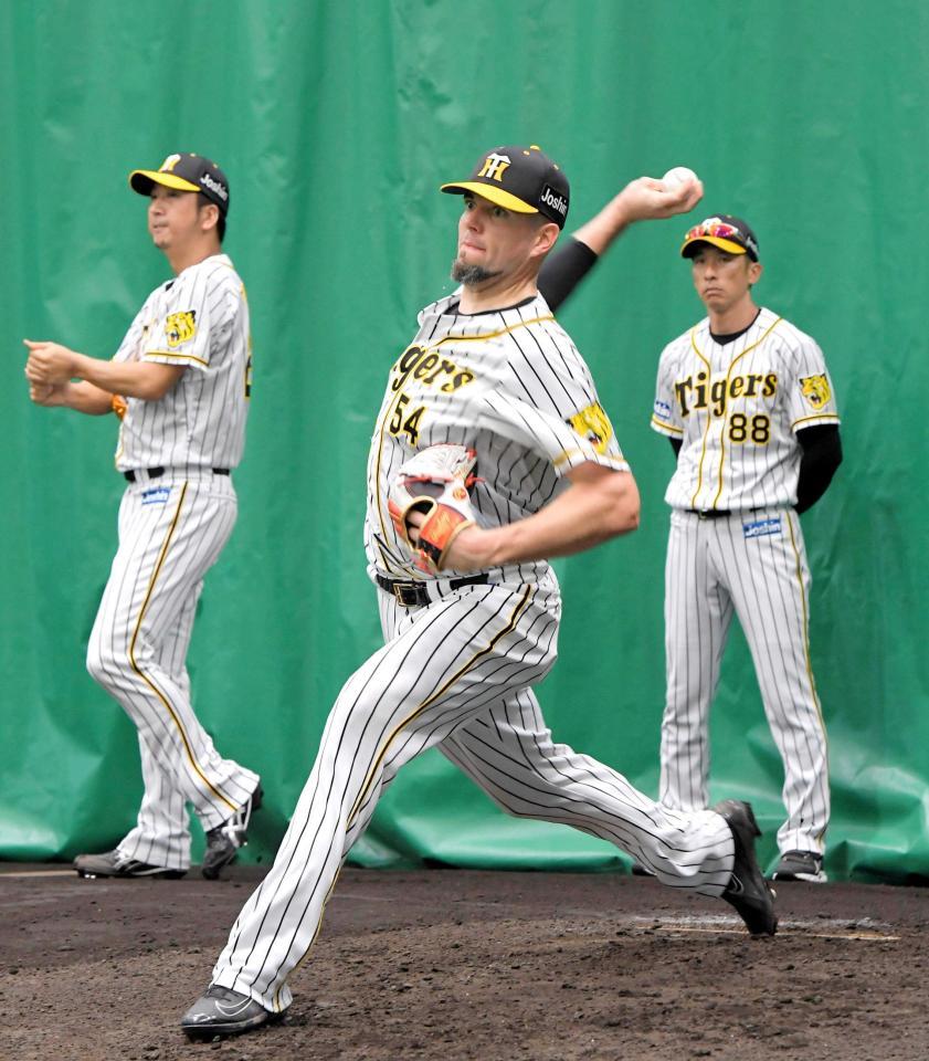 　矢野監督（右）の前で投球練習するメッセンジャー（撮影・北村雅宏）