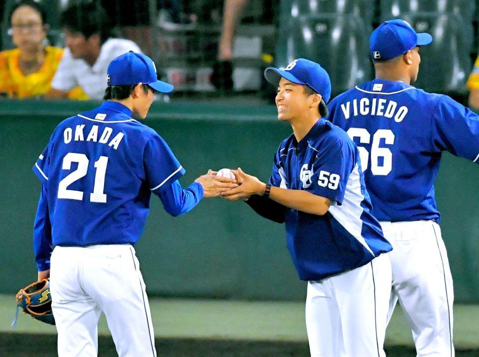 最後を締めた岡田（左）から、プロ初勝利のウイニングボールを嬉しそうに受け取る山本（撮影・吉澤敬太）