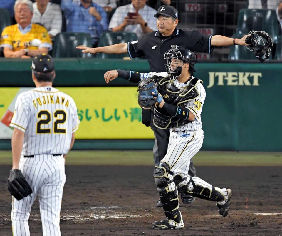 　９回、巨人・山本を三振に仕留め、一塁に送球し振り逃げを阻止する梅野。手前は藤川（撮影・高部洋祐）