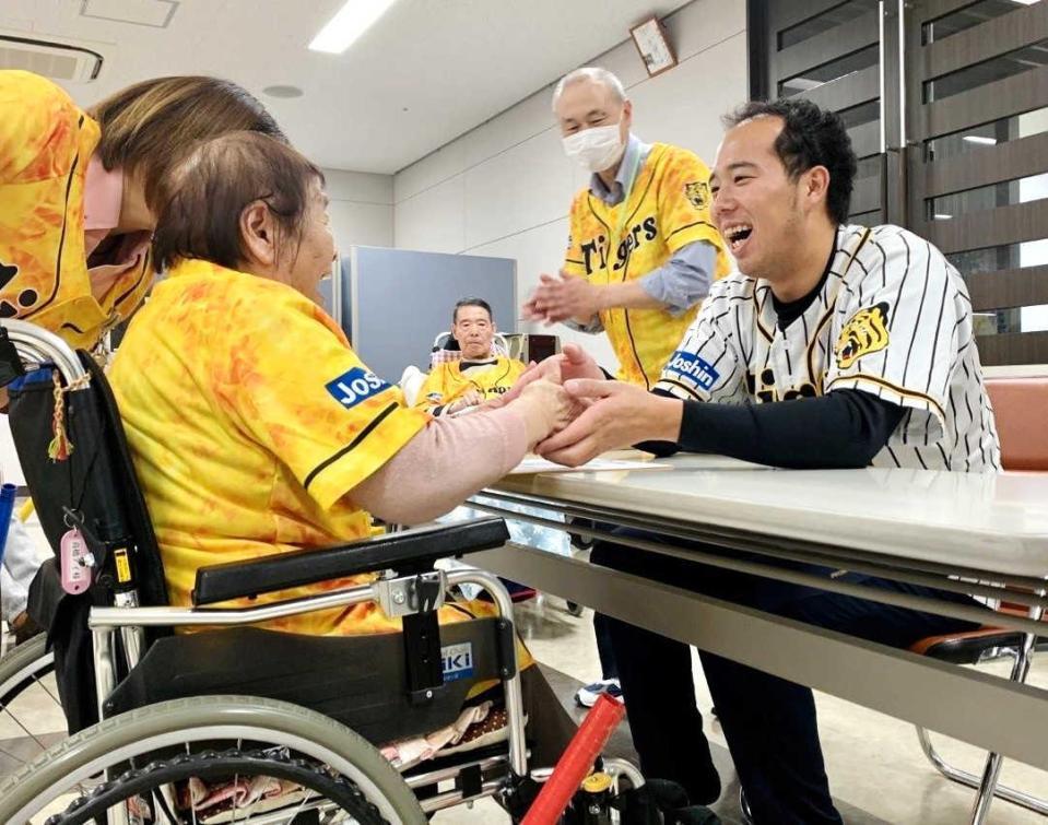 　入居者にサイン色紙を手渡し握手する青柳