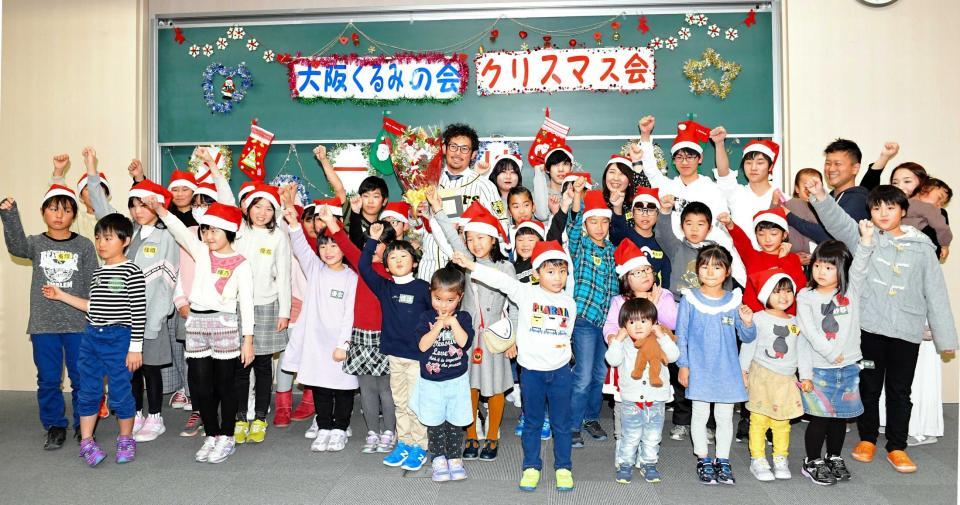 　大阪くるみの会のクリスマス会に参加し、集合写真に納まる岩田（中央）