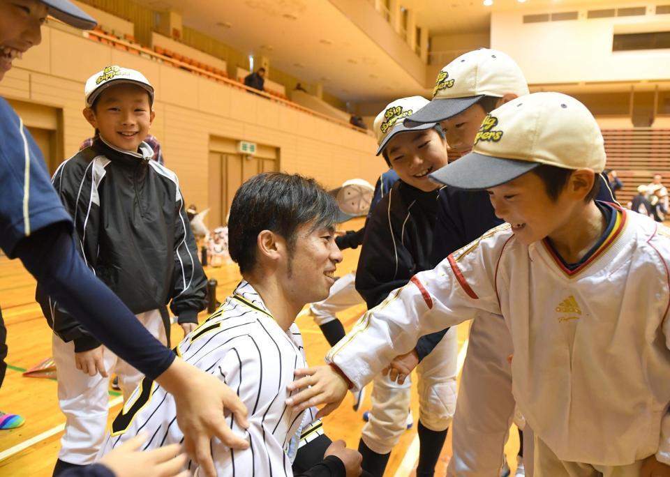 　腕相撲で対決し、かなわないことを察した子どもたちは羨望（せんぼう）のまなざしで江越の右肩を触わる（撮影・北村雅宏）