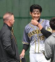 　投手陣の１日キャプテンを務め、元阪神のジェフ　ウィリアムス氏（左）に額の「ＣＡＰＴＡＩＮ」を見られる阪神・藤浪晋太郎