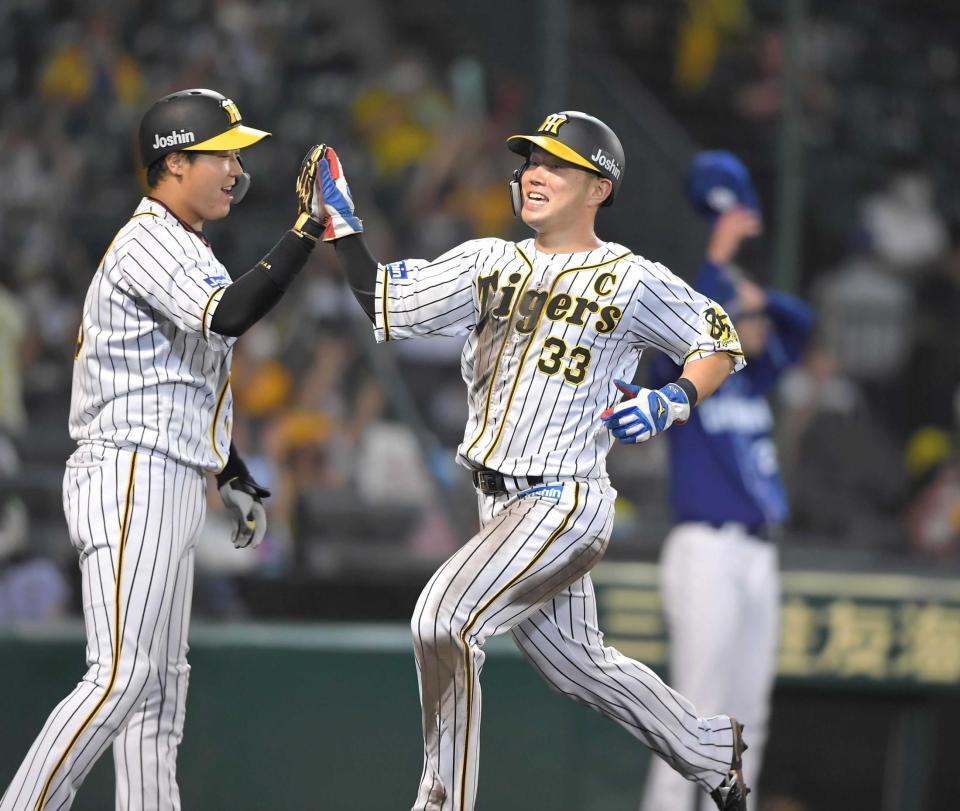 　５回、糸井の適時打で生還した糸原（右）は、大山とタッチを交わす