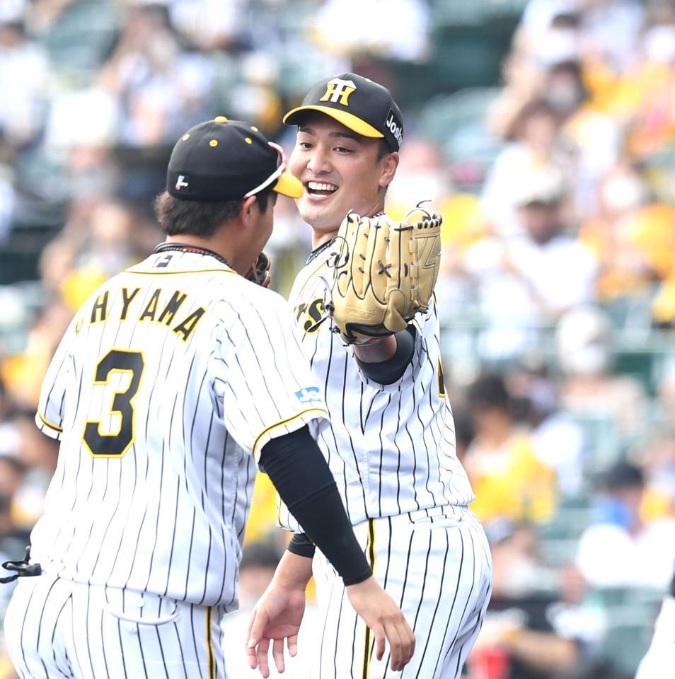 １回、好守の阪神・大山悠輔と笑顔でグラブタッチを交わす阪神・秋山拓巳＝甲子園（撮影・飯室逸平）