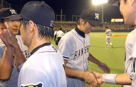 　プロ初勝利を挙げ、ナインと握手する藤川（右）と佐藤コーチ（左奥）＝０２年９月１１日