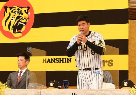 タテジマのユニフォームに袖を通し、あいさつする阪神・佐藤輝明。矢野燿大監督＝大阪市内のホテル（撮影・田中太一）