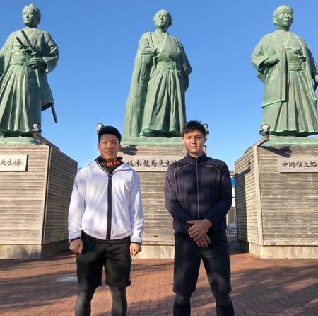 土佐三志士の像の前でカメラにおさまる石井（左）と栄枝（球団提供）