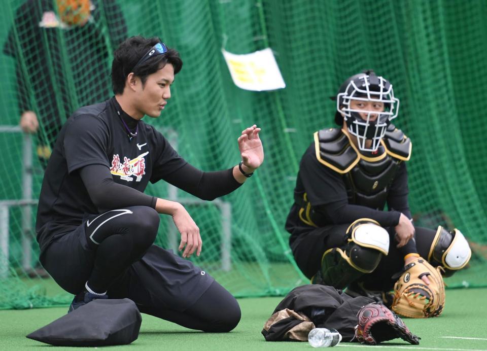 　ブルペンでの投球後、坂本（右）と話する藤浪