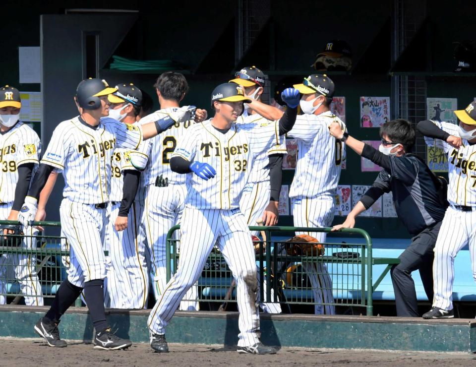 　４回、原口の２点打で生還し、ナインにタッチで迎えられる井上（手前中央）と佐藤輝（同左）