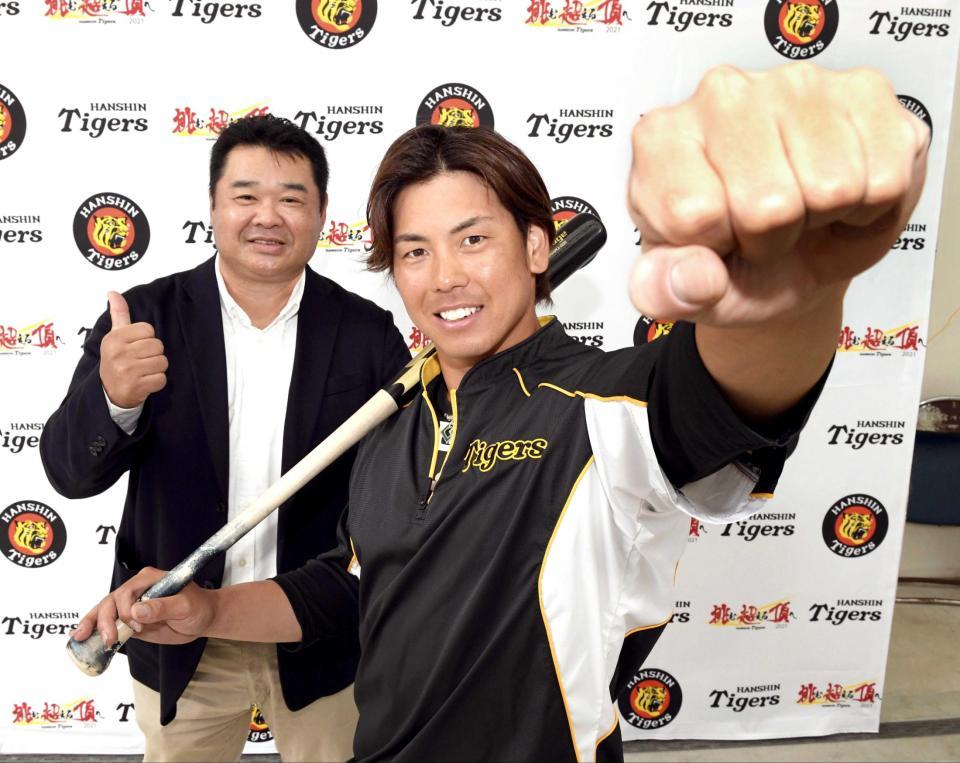 　拳を突き上げて笑顔を見せる梅野。西山秀二氏（左）は守備はもちろん、打力にも期待を寄せる。※フォトセッション時のみ、マスクを外してます（撮影・田中太一）