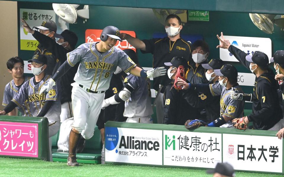 　９回、高山の犠飛で生還し笑顔でナインとタッチを交わす佐藤輝（撮影・飯室逸平）