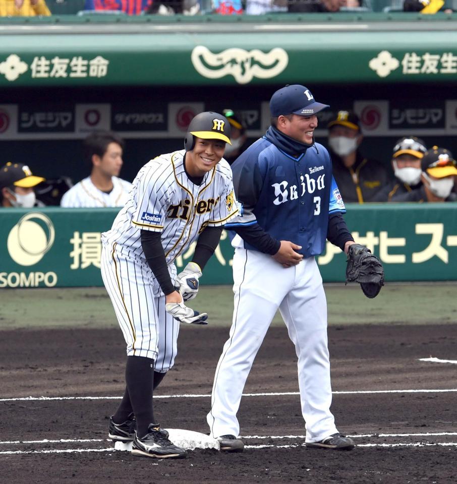 　２回、佐藤輝は四球で出塁し、塁上で山川に声を掛けられ笑顔を見せる（撮影・山口登）