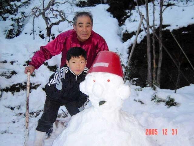 　雪だるまを作る佐藤輝（前方）と祖父の勲さん（後方）