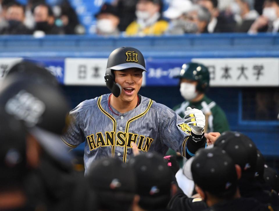 　２回、先制犠飛を放った佐藤輝はベンチ前でナインとタッチを交わす