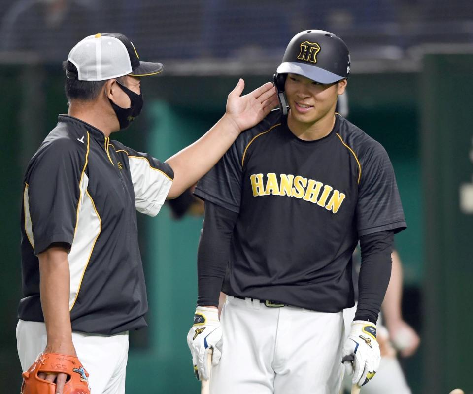 　打撃練習後、阪神・佐藤輝を指導する阪神・井上コーチは空手チョップ！？を繰り出す＝東京ドーム（撮影・田中太一）