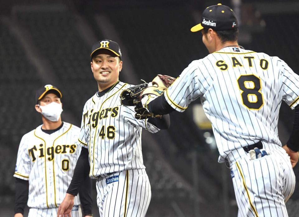 　７回、安部の打球を好捕した佐藤輝（右）とタッチする