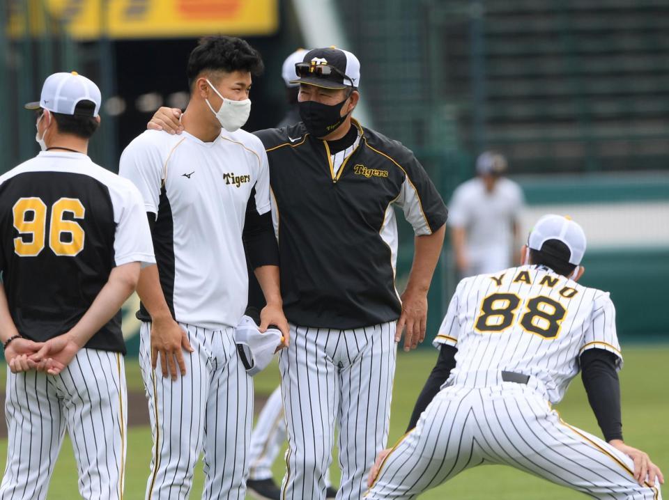 練習前、井上コーチと話をする佐藤輝。右手前は矢野監督（撮影・田中太一）