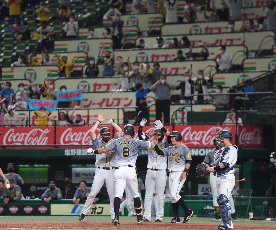 　９回、右中間に勝ち越し３ランを放ち迎えられる佐藤輝（撮影・金田祐二）