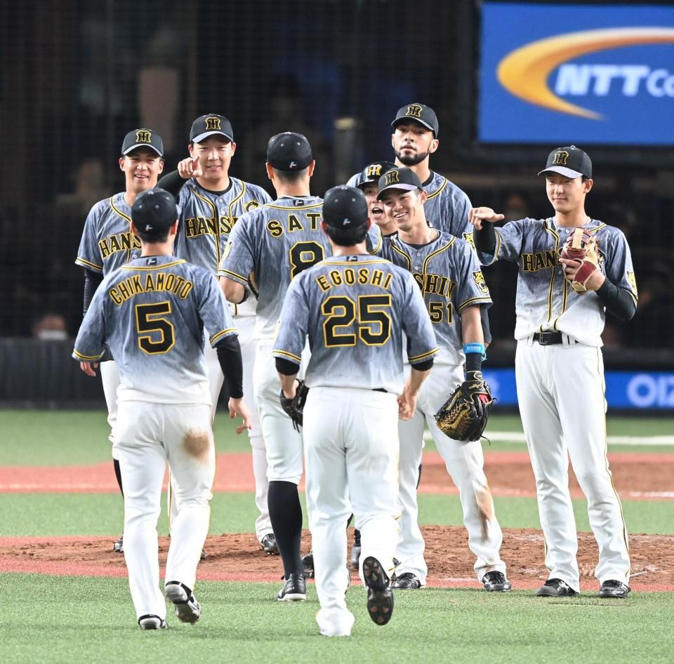 　試合に勝利し、笑顔のナインにＺポーズで迎えられる佐藤輝（８）＝撮影・高石航平