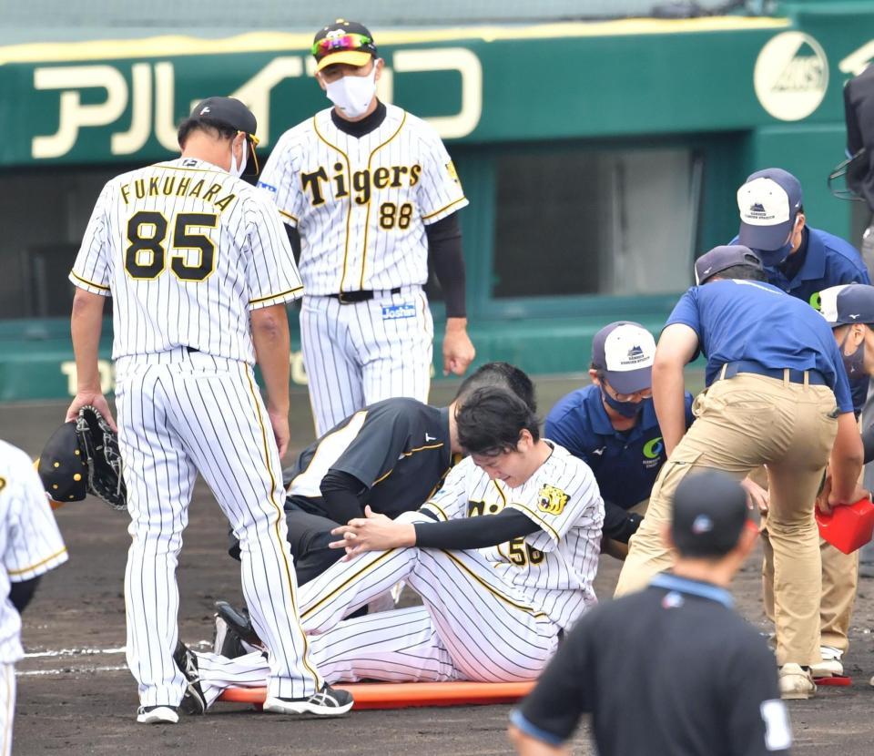 　７回、栗原の投ゴロを捕球した際に、左足を負傷し退場となる小林（中央）。中央奥は矢野監督（撮影・吉澤敬太）