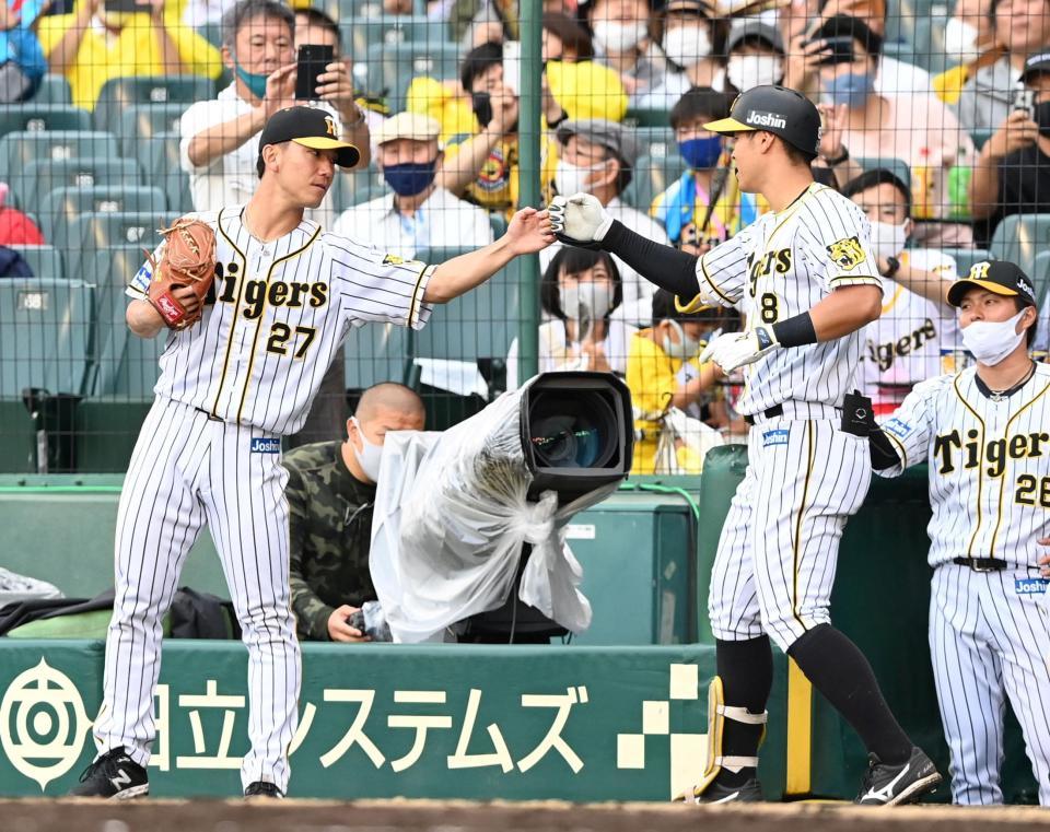６回、ソロを放った阪神・佐藤輝明とタッチを交わす阪神・伊藤将司＝甲子園（撮影・飯室逸平）