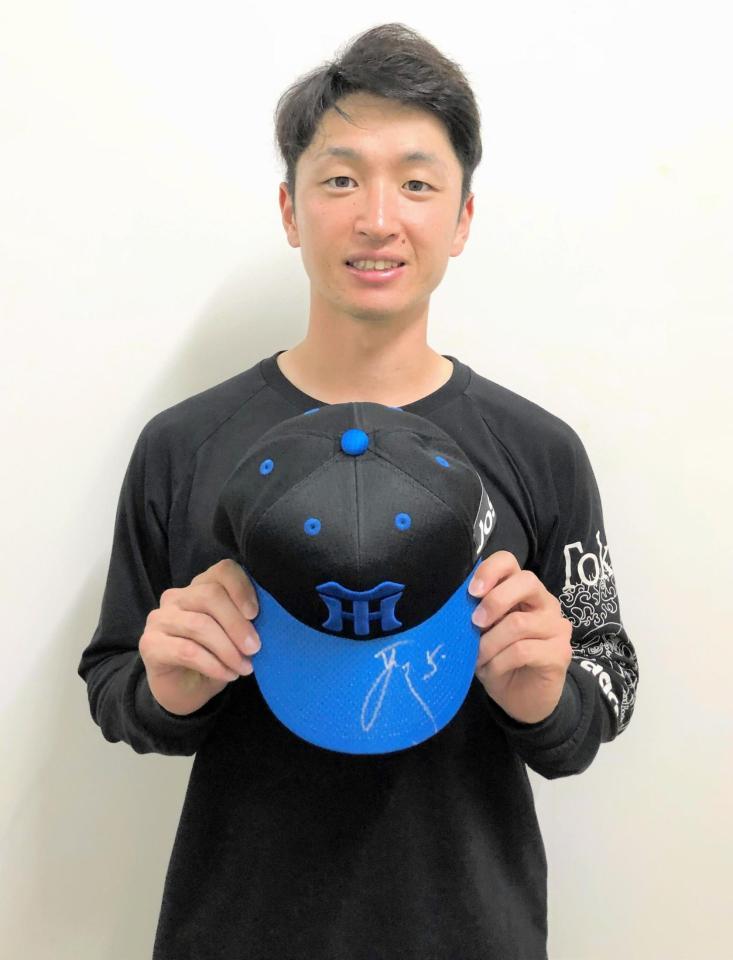 　サイン入りした青色キャップを手に持つ近本（球団提供）