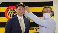 　入団会見で嶌村球団本部長（右）から帽子をかぶせてもらう二保（代表撮影）