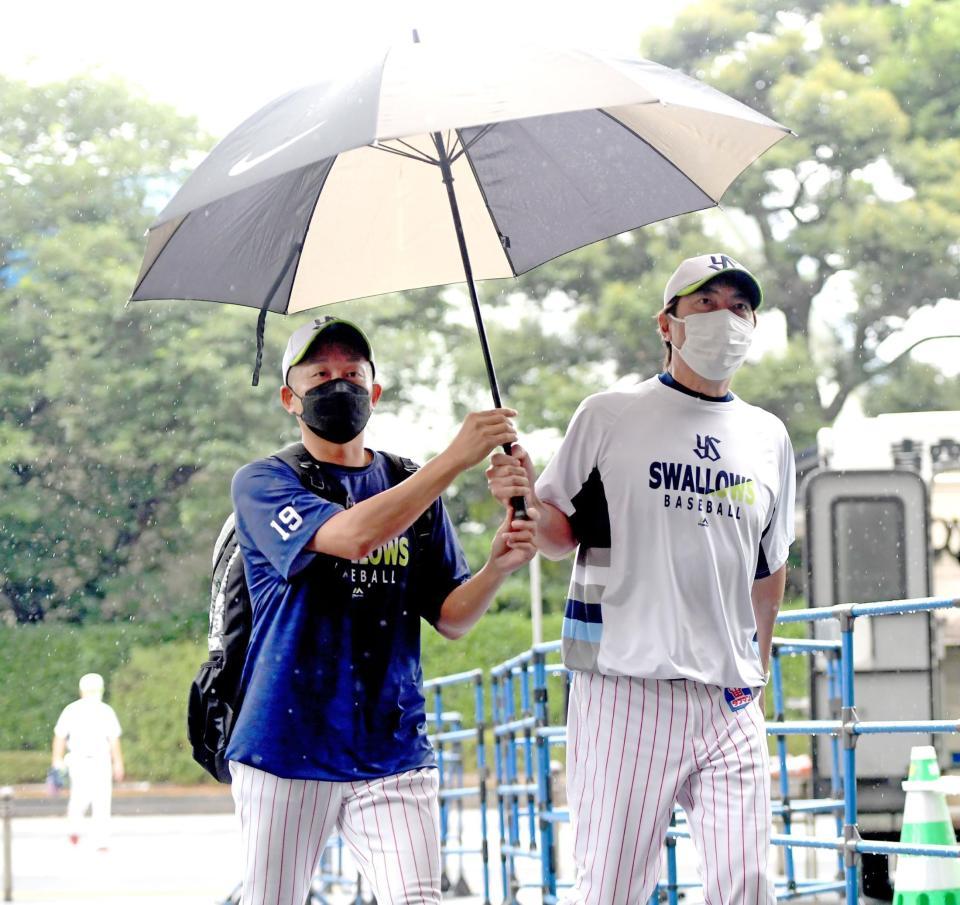 　相合い傘で歩く高津監督と石川（撮影・金田祐二）
