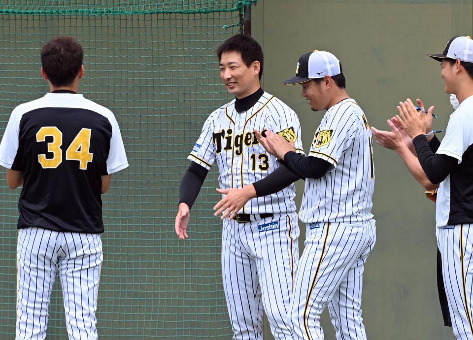 　チーム合流した岩崎（中央左）は西勇（中央右）らナインから拍手で迎えられる