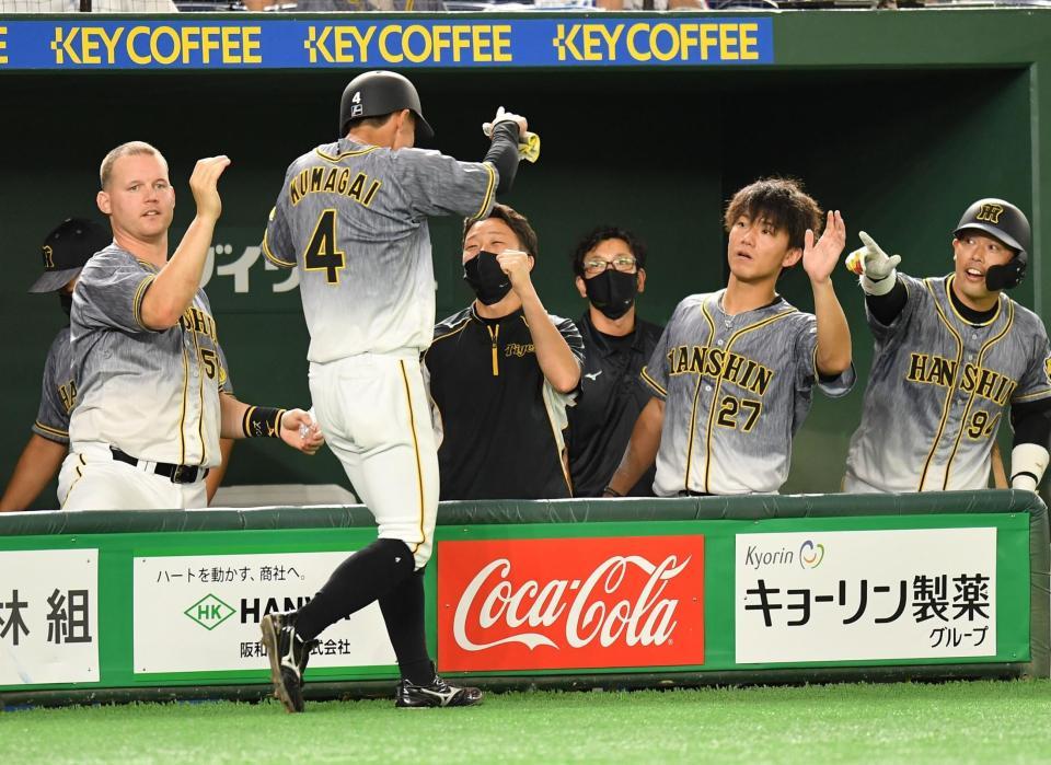 ８回、ロハスの押し出し死球で生還した熊谷（４）を迎える伊藤将（右から２人目）ら阪神ナイン＝東京ドーム（撮影・西岡正）