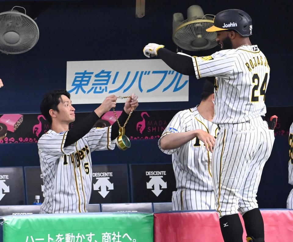 　８回、メダルを手にメル・ロハス・ジュニアを迎える近本光司（撮影・飯室逸平）