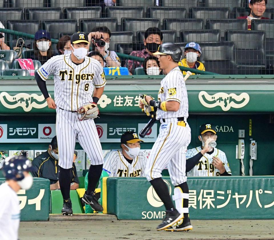 　１回　空振り三振に倒れベンチに戻る糸井（手前）を見つめるベンチスタートの佐藤輝（左）と矢野監督（右奥）