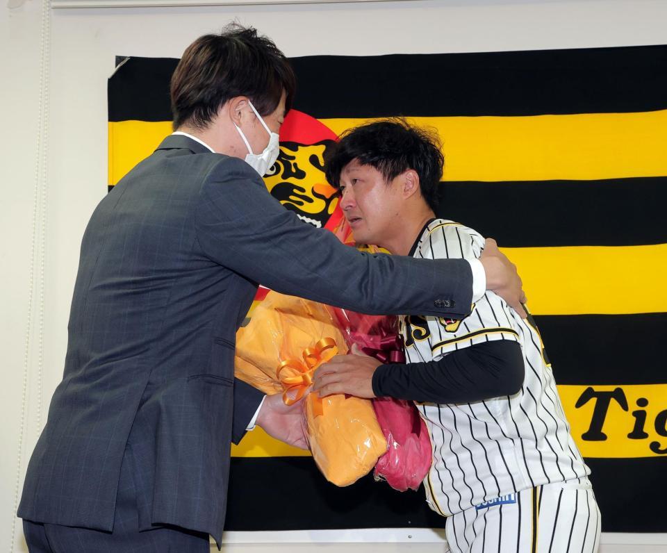 　引退会見で俊介（右）は新井コーチから花束を贈られる