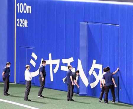 　試合後、球場関係者が外野フェンスを確認する（撮影・山口登）