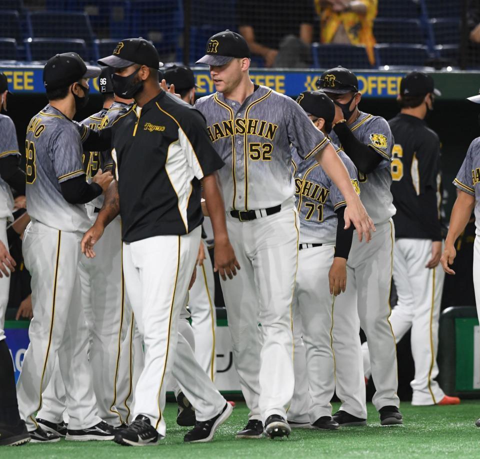 　矢野監督（左）に迎えられる阪神・サンズ（中央）＝東京ドーム（撮影・佐藤厚）