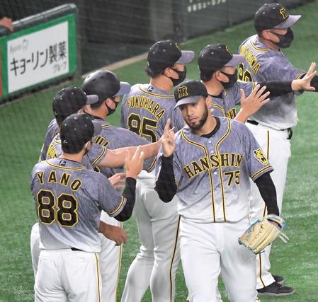 　無失点に抑えて巨人に勝利し、矢野監督（左）に迎えられるスアレス（撮影・西岡正）
