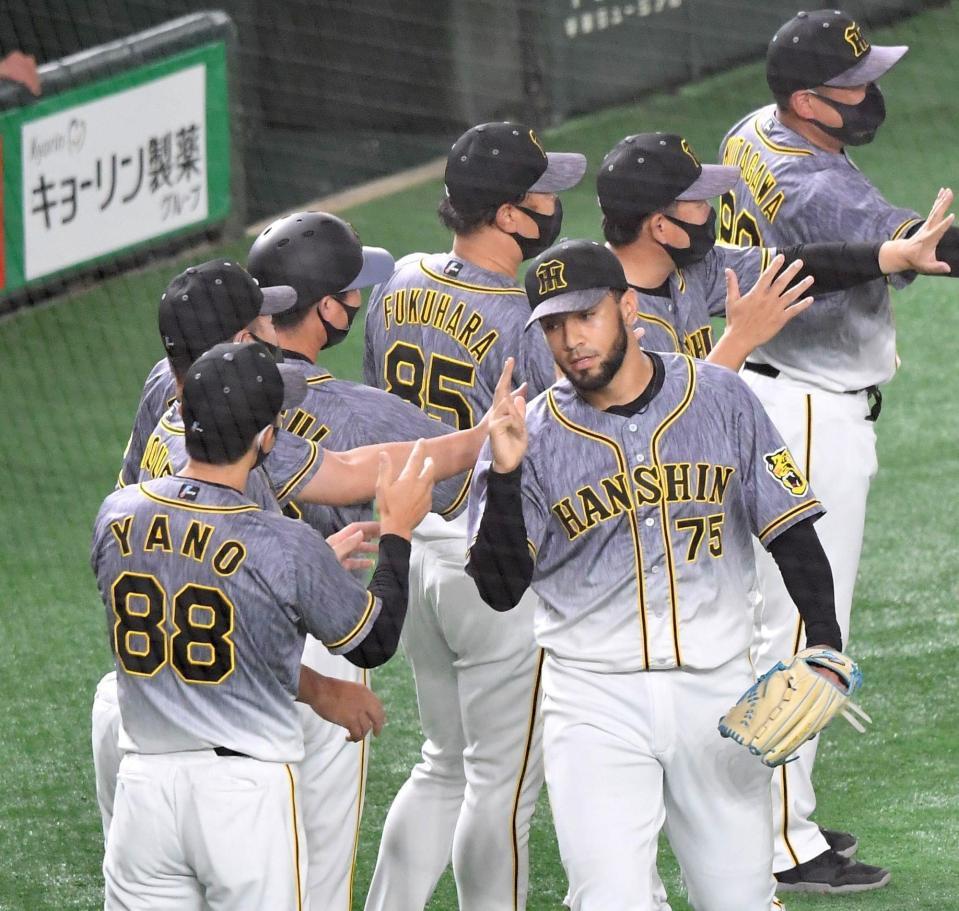 　無失点に抑えて巨人に勝利し、矢野監督（左）に迎えられるスアレス（撮影・西岡正）