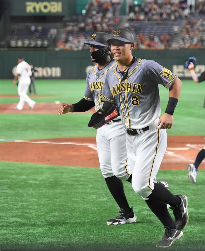 ２回、近本の先制打で生還し、ロハス（奥）とベンチへ向かう佐藤輝（撮影・西岡正）