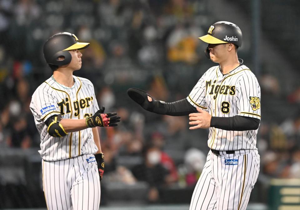　３回、先制のホームを踏み、伊藤将（左）とタッチを交わす佐藤輝（撮影・飯室逸平）