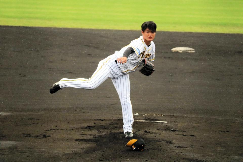 雨の中、帽子を飛ばし力投する西純