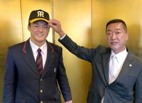 仮契約し、山本スカウト（右）から帽子をかぶせてもらう前川（球団提供）