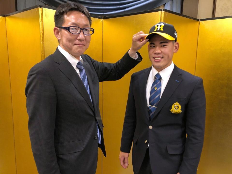 　仮契約を終え、吉野スカウト（左）から帽子をかぶせてもらう鈴木（阪神タイガース提供）