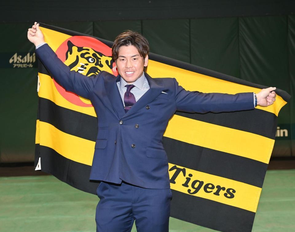 　球団旗を手にポーズを決める梅野（撮影・飯室逸平）